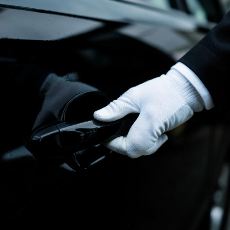 Chauffeur in a white glove opening the door of an AOC vehicle